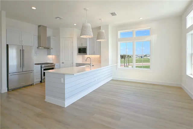 a kitchen with kitchen island a counter top space a sink stainless steel appliances and cabinets