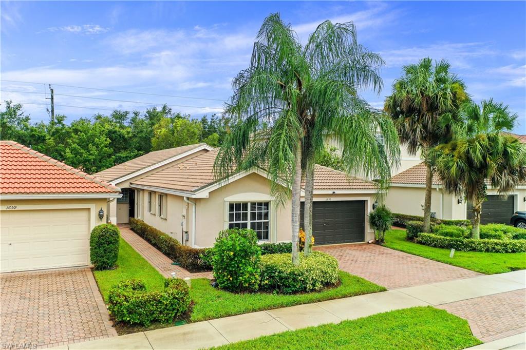 1655 Triangle Palm Terrace Naples, FL 34119 - Photo 3 of 22 a front view of a house with a garden and a yard