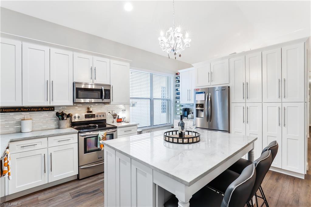 1655 Triangle Palm Terrace Naples, FL 34119 - Photo 8 of 22 a kitchen with stainless steel appliances kitchen island granite countertop a dining table and a refrigerator