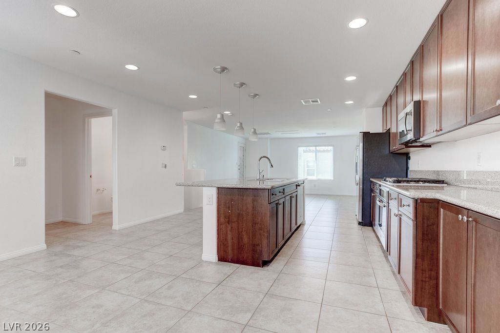 4650 Ranch House Road, Unit 47 North Las Vegas, NV 89031 - Photo 13 of 43 An open concept kitchen features warm wooden cabinetry, granite counters, and a central island with pendant lighting.