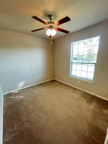 an empty room with a window and a ceiling fan