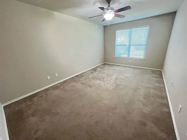 an empty room with a window and a fan