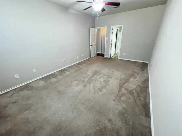 an empty room with a chandelier fan and windows