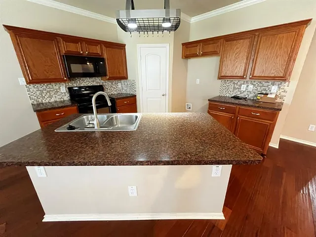 a kitchen with kitchen island granite countertop a sink stove and microwave