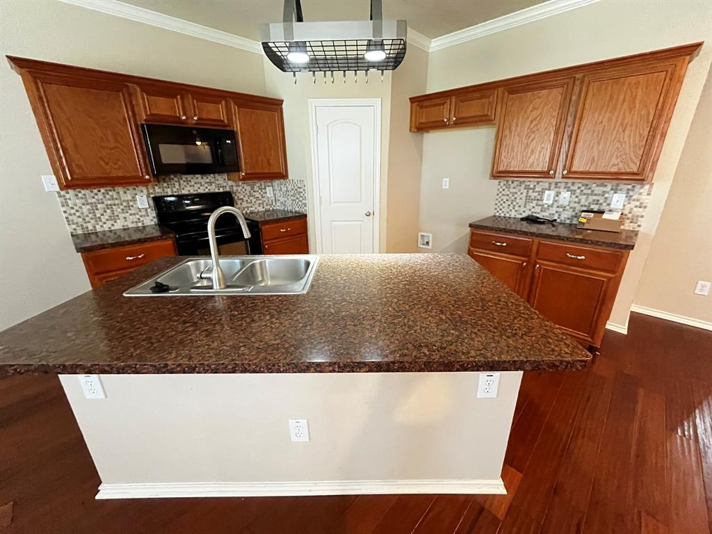 129 Sierra Drive Waxahachie, TX 75167 - Photo 6 of 24 a kitchen with kitchen island granite countertop a sink stove and microwave