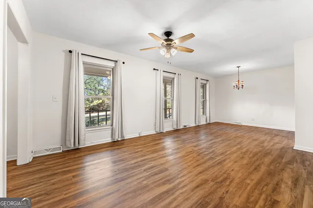 an empty room with wooden floor and a ceiling fan