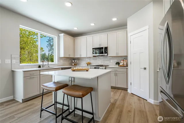 a kitchen with a refrigerator a stove top oven a sink dishwasher and white cabinets with wooden floor