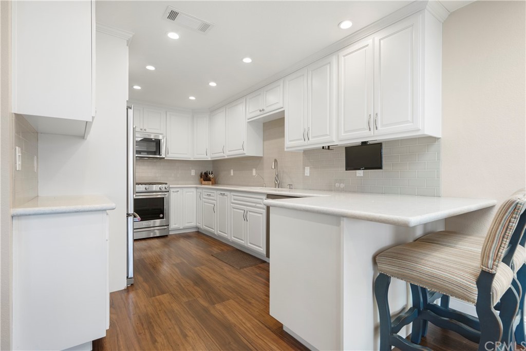 5965 Maybrook Circle Riverside, CA 92506 - Photo 13 of 34 a kitchen with white cabinets and wooden floor