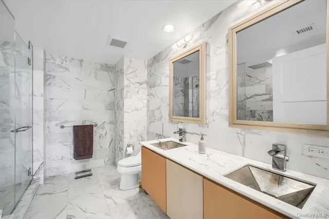 a bathroom with a sink toilet double vanity and shower