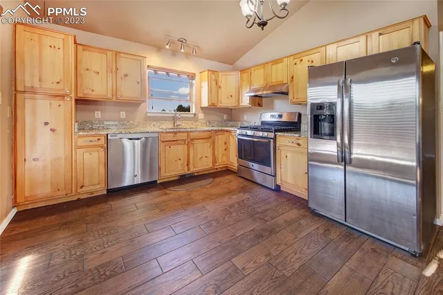 a kitchen with granite countertop stainless steel appliances a refrigerator and cabinets