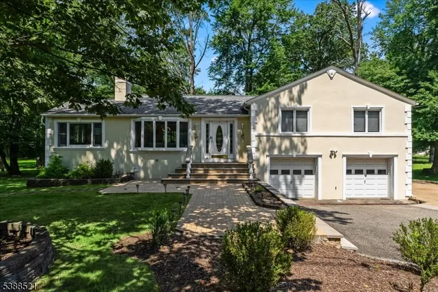 a view of a white house next to a yard with plants and trees