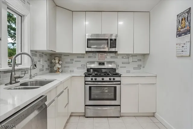 a kitchen with stainless steel appliances granite countertop a sink stove oven and white cabinets