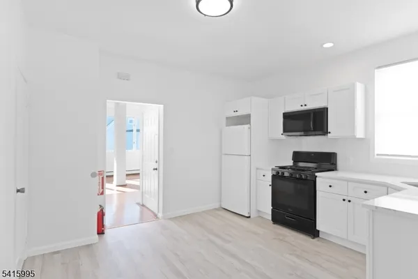 a view of a kitchen with wooden floor and electronic appliances