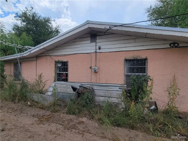 a backyard of a house with plants and barbeque oven