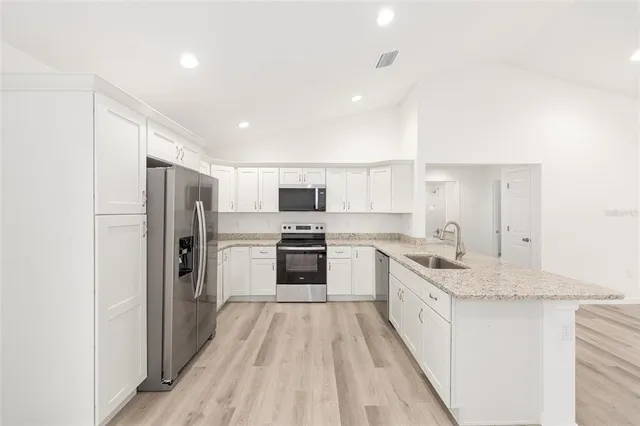 an empty room with wooden floor ceiling fan and windows