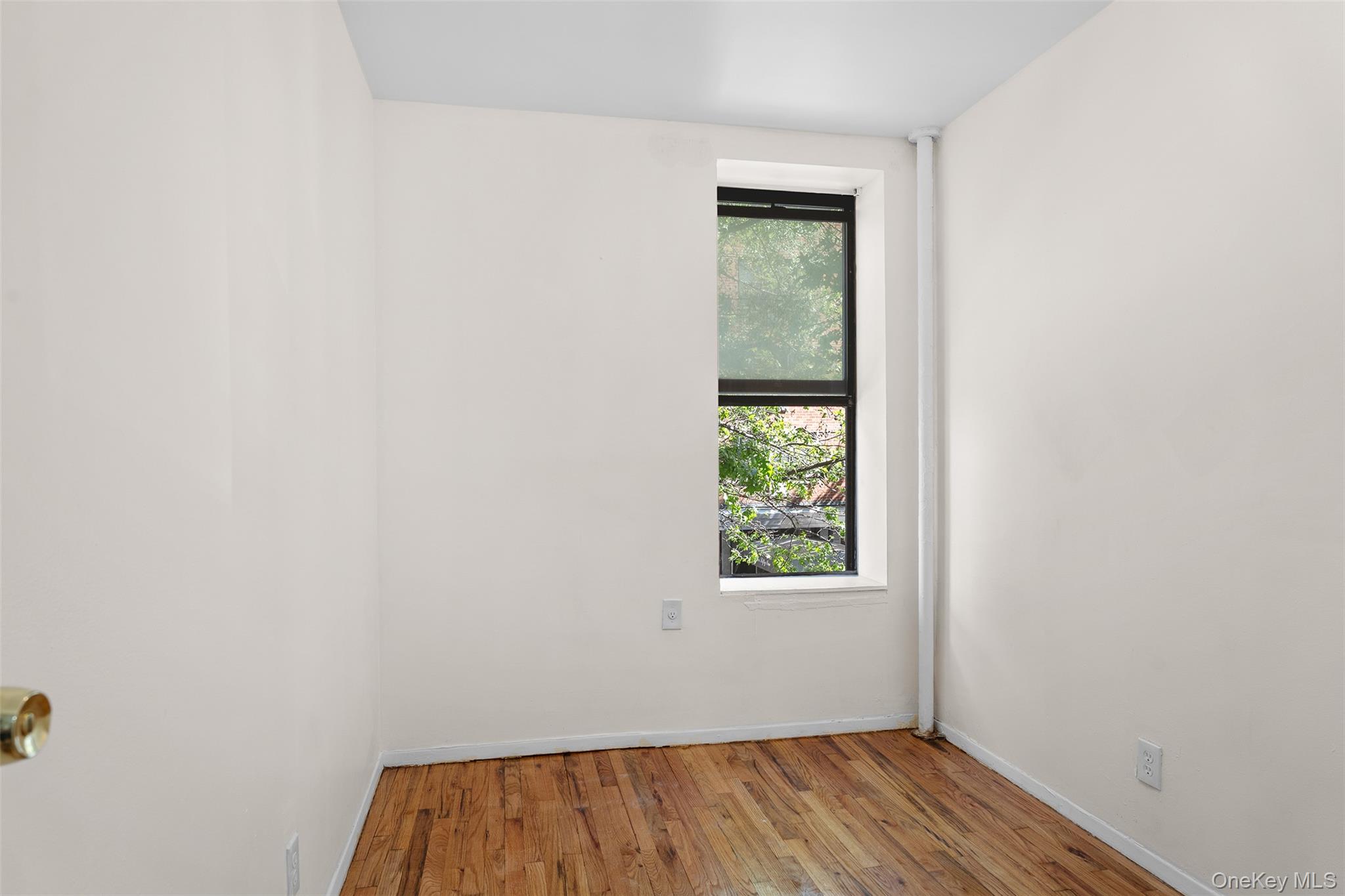 246 East 51st Street, Unit 7 Manhattan, NY 10022 - Photo 7 of 9 a view of an empty room with wooden floor and a window