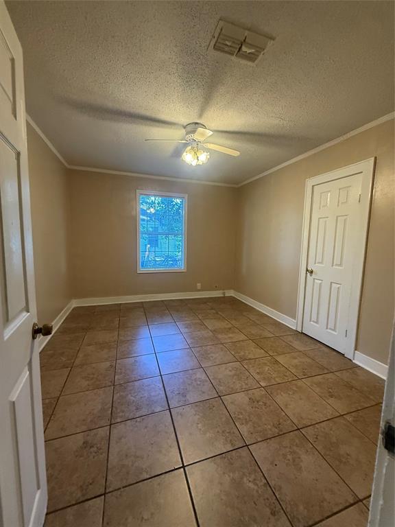 217 3rd St Pinehill Springhill, LA 71075 - Photo 14 of 23 Room featuring large format tile flooring, a window offering natural light, a ceiling fan with integrated lighting, and crown molding