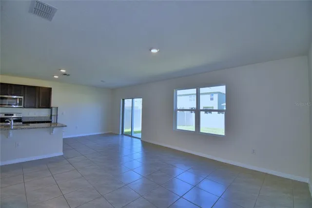 a view of an empty room with a kitchen and a window