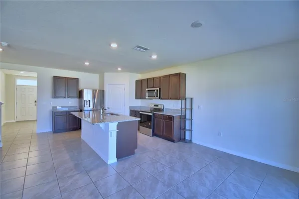 a large open kitchen with a refrigerator a stove top oven and a sink
