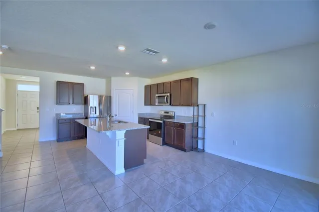 a large open kitchen with a refrigerator a stove top oven and a sink