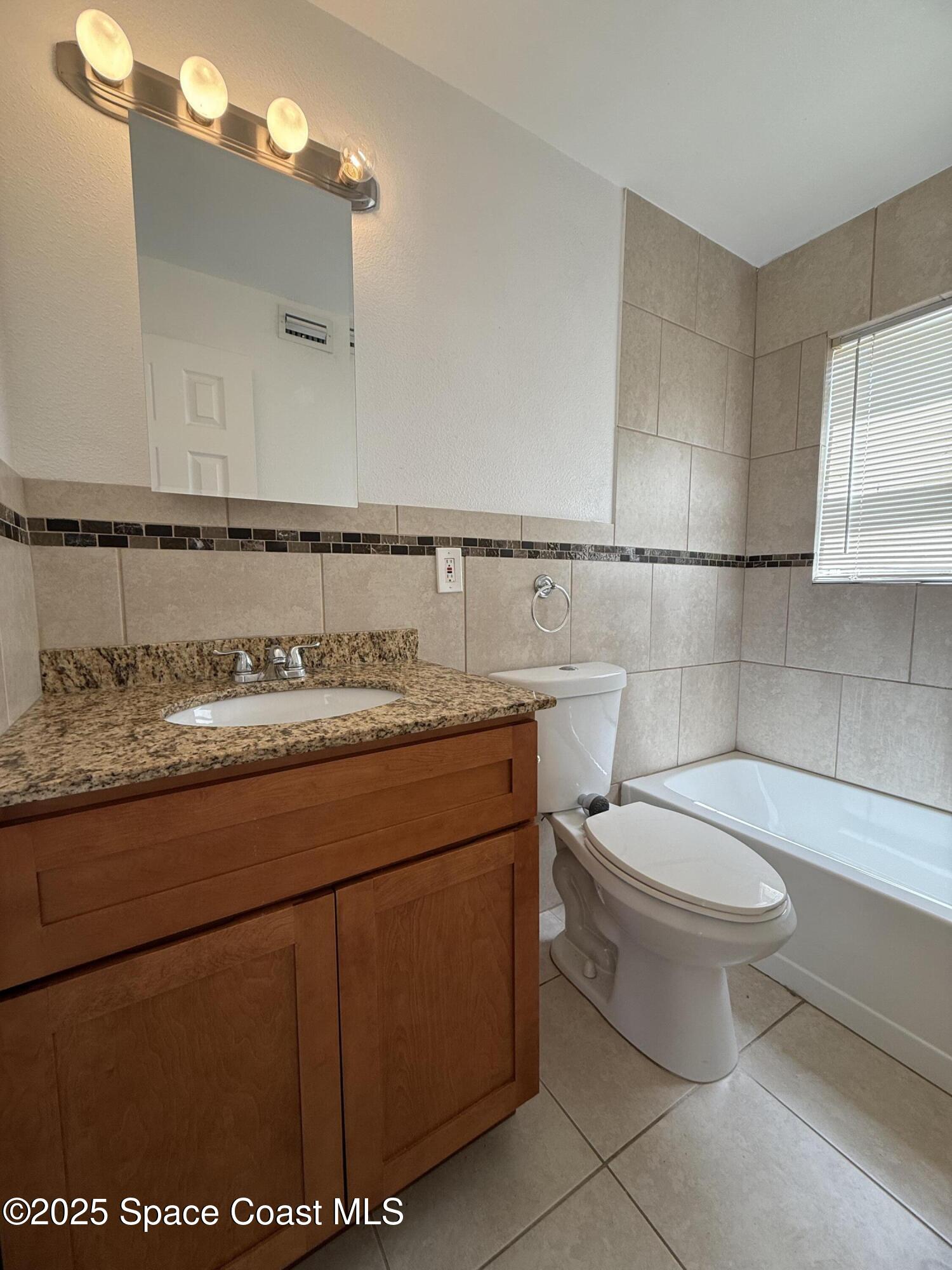 1440 Parkway Drive, Unit 8A Melbourne, FL 32935 - Photo 7 of 21 a bathroom with a granite countertop toilet and a sink