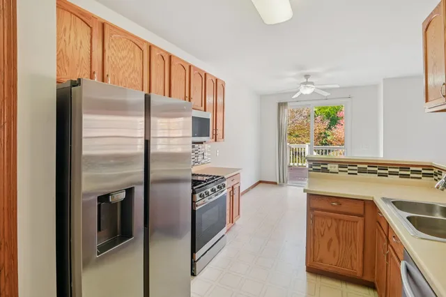 a kitchen with stainless steel appliances granite countertop a refrigerator a stove and a sink with large window