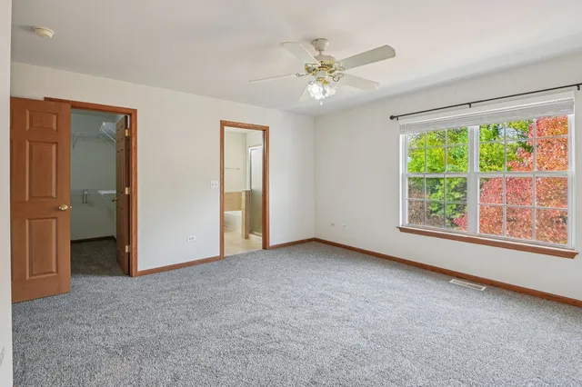 an empty room with windows closet and chandelier fan
