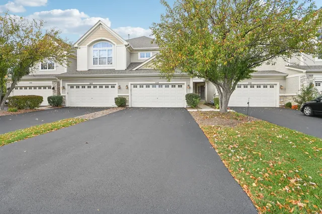 a view of a white house with a yard and large tree