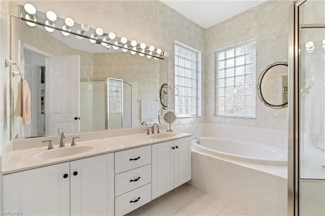 a bathroom with a double vanity sink mirror and a bathtub