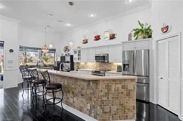 a kitchen with stainless steel appliances kitchen island granite countertop a refrigerator a stove and white cabinets