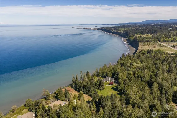 an aerial view of a house with a yard and ocean view