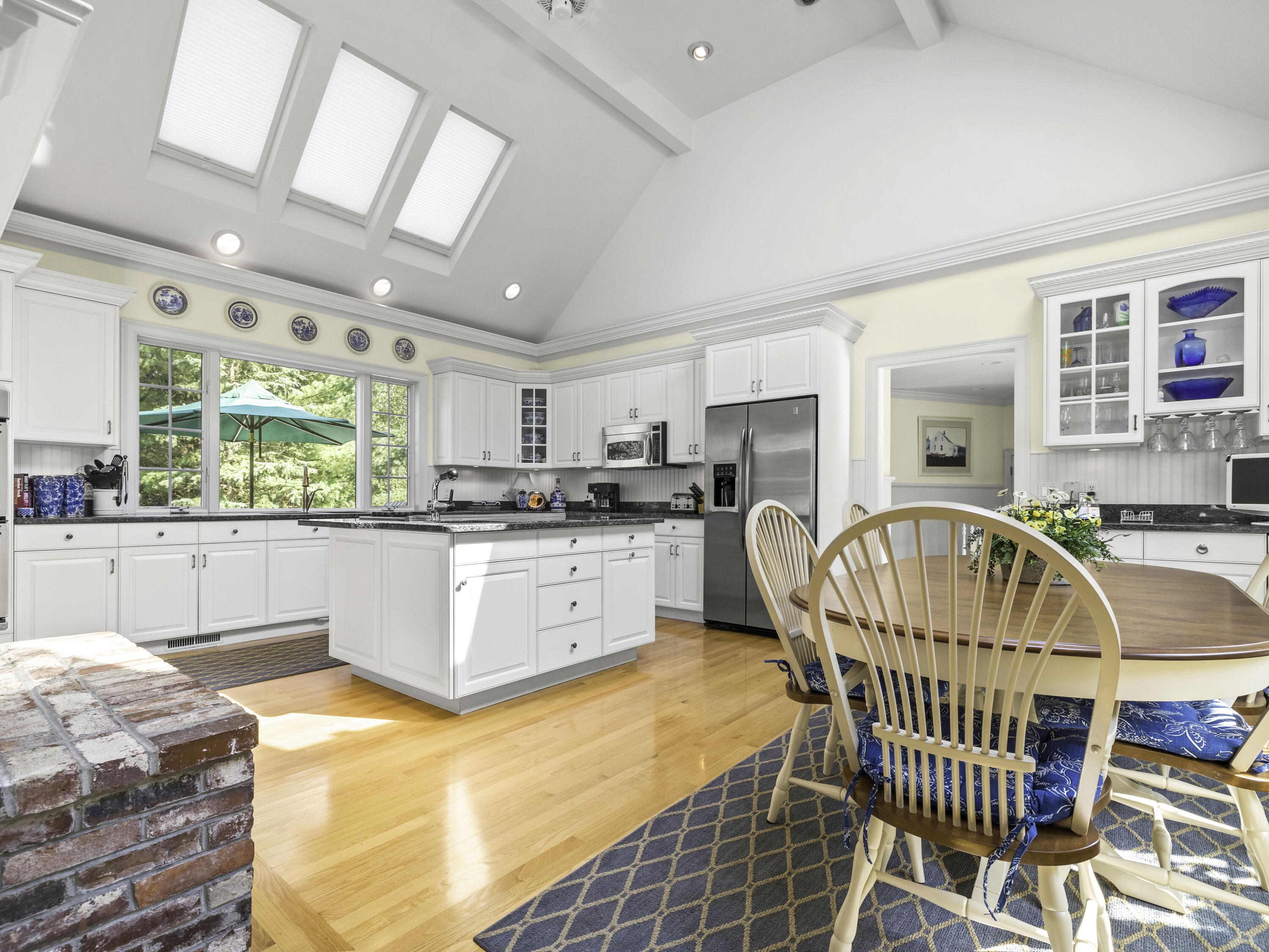 405 Baxter Neck Road Marstons Mills, MA 02648 - Photo 7 of 36 a kitchen with stainless steel appliances kitchen island granite countertop a stove a sink a dining table and chairs with wooden floor