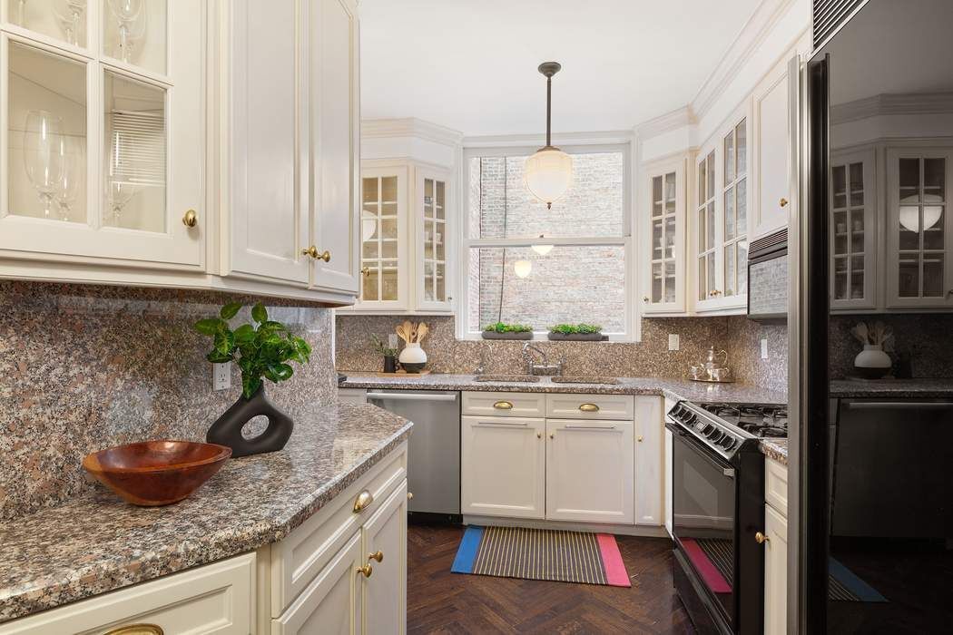 11 East 73rd Street, Unit 1D Manhattan, NY 10021 - Photo 10 of 18 a kitchen with stainless steel appliances granite countertop a sink a stove and a wooden cabinets