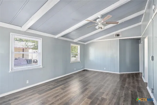 a view of an empty room with wooden floor and a window