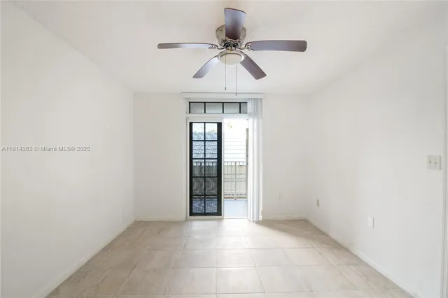 an empty room with a chandelier fan and windows
