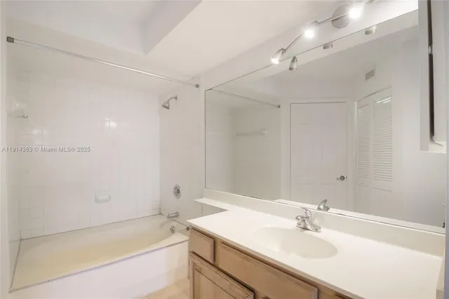 a bathroom with a tub sink vanity granite and a mirror