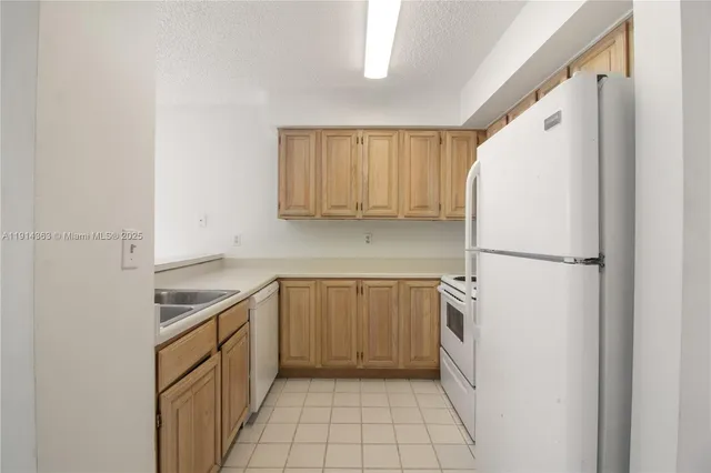 a kitchen with a sink a refrigerator and cabinets