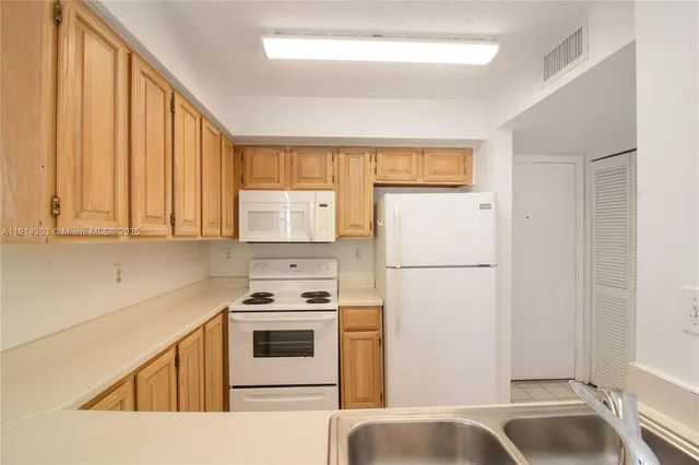 a kitchen with a refrigerator a stove top oven and cabinets