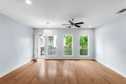 a view of an empty room with a window and wooden floor