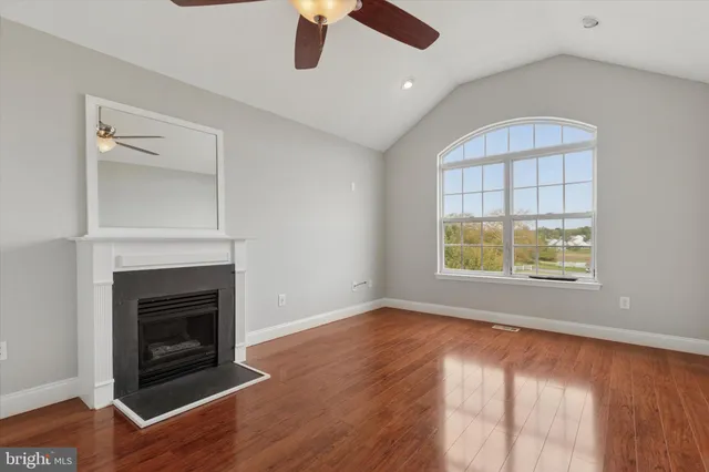 an empty room with windows a fireplace and wooden floor