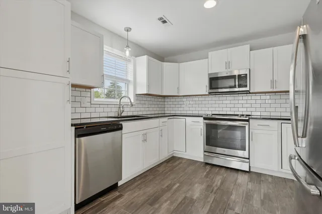 a kitchen with granite countertop white cabinets white stainless steel appliances and a sink
