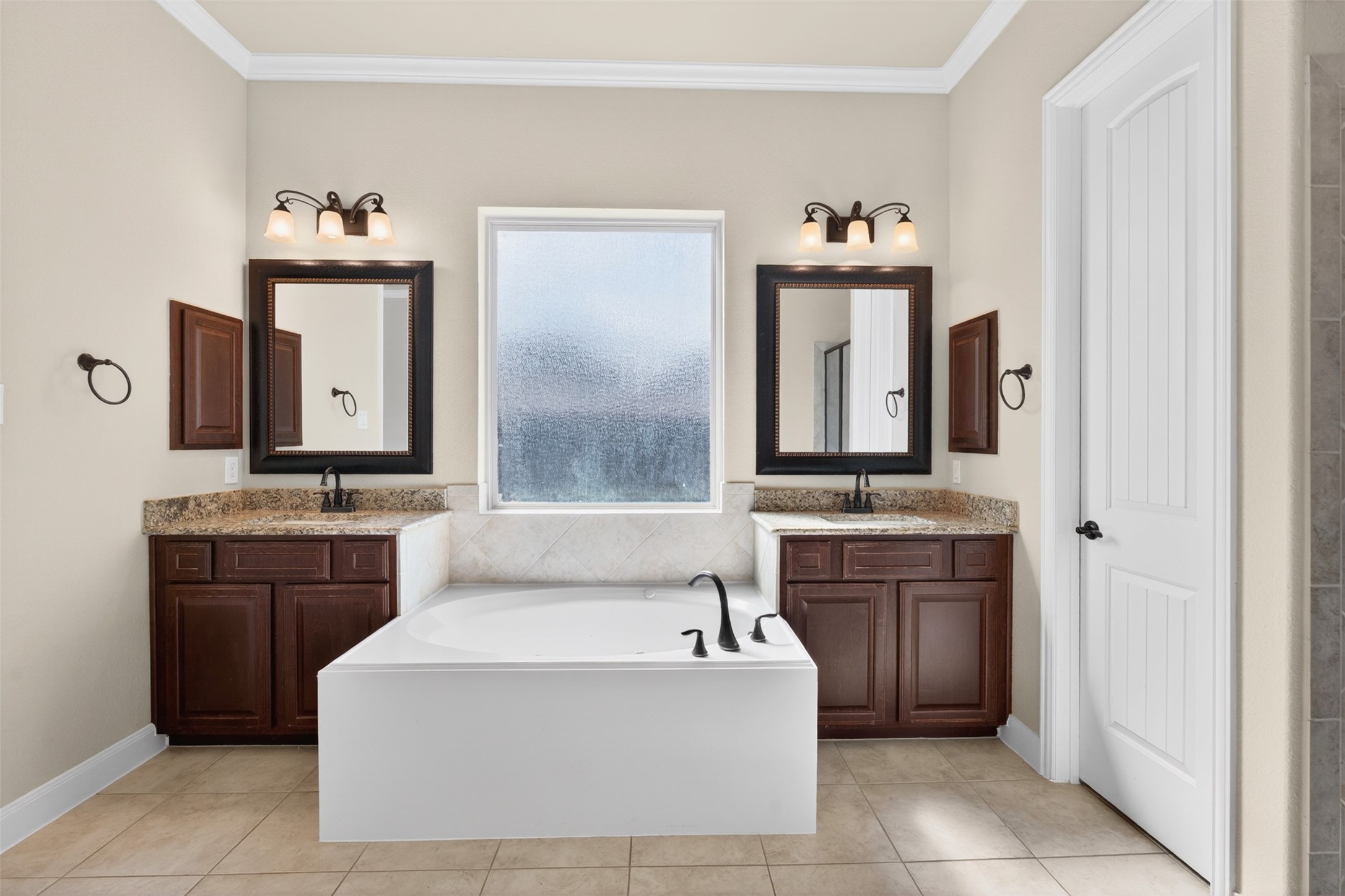 18202 Wedgewood Bluff Court Spring, TX 77379 - Photo 29 of 50 Dual vanity area with framed mirrors, wood cabinetry, and bright window.