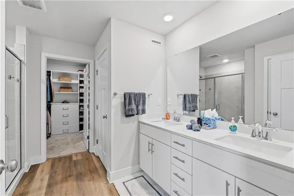 a spacious bathroom with a double vanity sink a mirror and shower