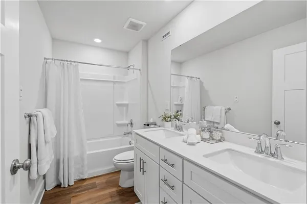 a bathroom with a double vanity sink toilet mirror and shower