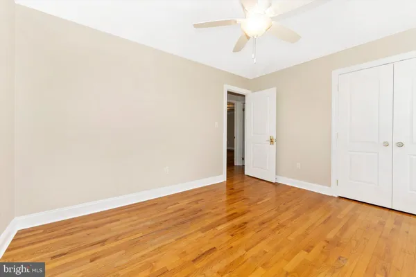 an empty room with a ceiling fan and wooden floor