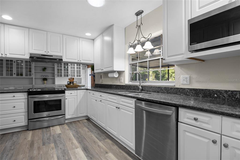 2110 Northwest 46th Street Gainesville, FL 32605 - Photo 5 of 31 a kitchen with stainless steel appliances granite countertop a sink a stove a microwave and wooden cabinets