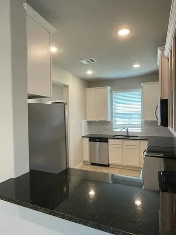 a kitchen with granite countertop white cabinets appliances and a sink