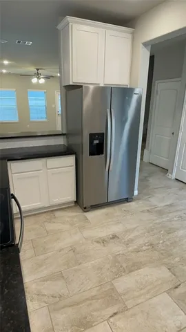an empty room with a chandelier fan and windows
