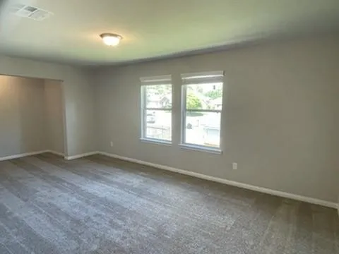 an empty room with windows and fan