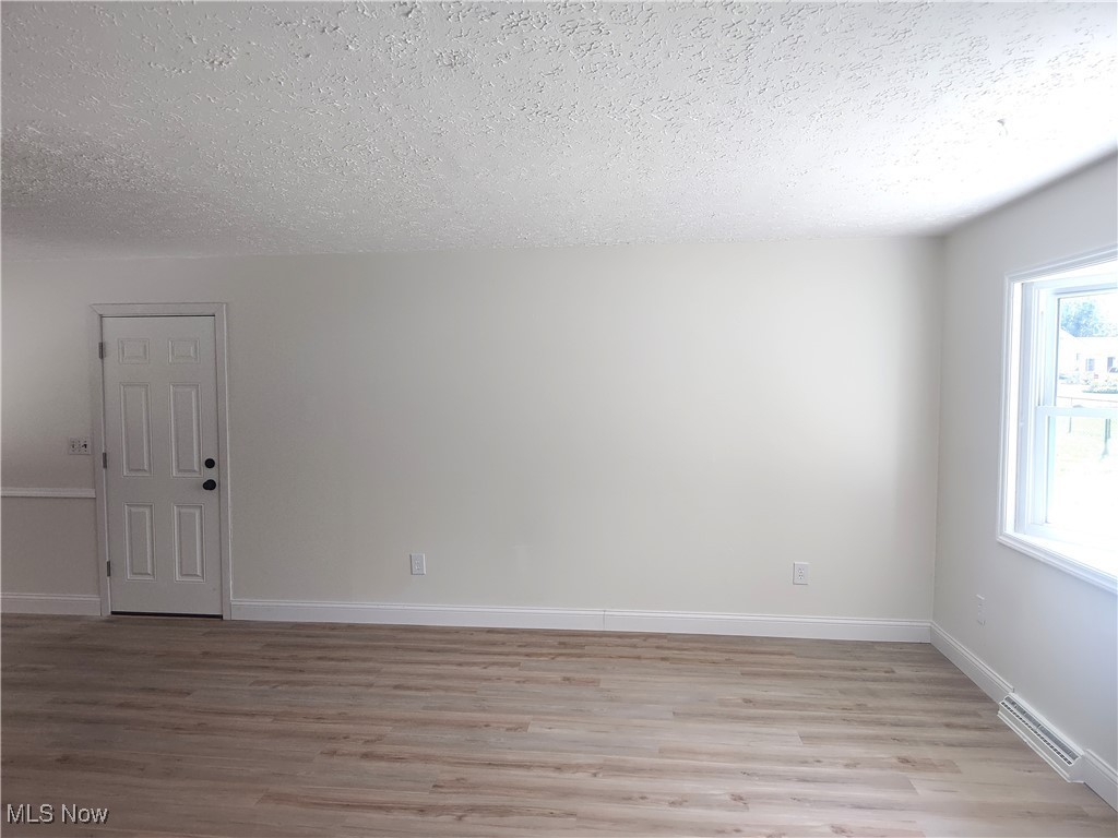8016 Ninevah Road Geneva, OH 44041 - Photo 16 of 45 Spare room with light wood-style floors, a textured ceiling, and a baseboard radiator